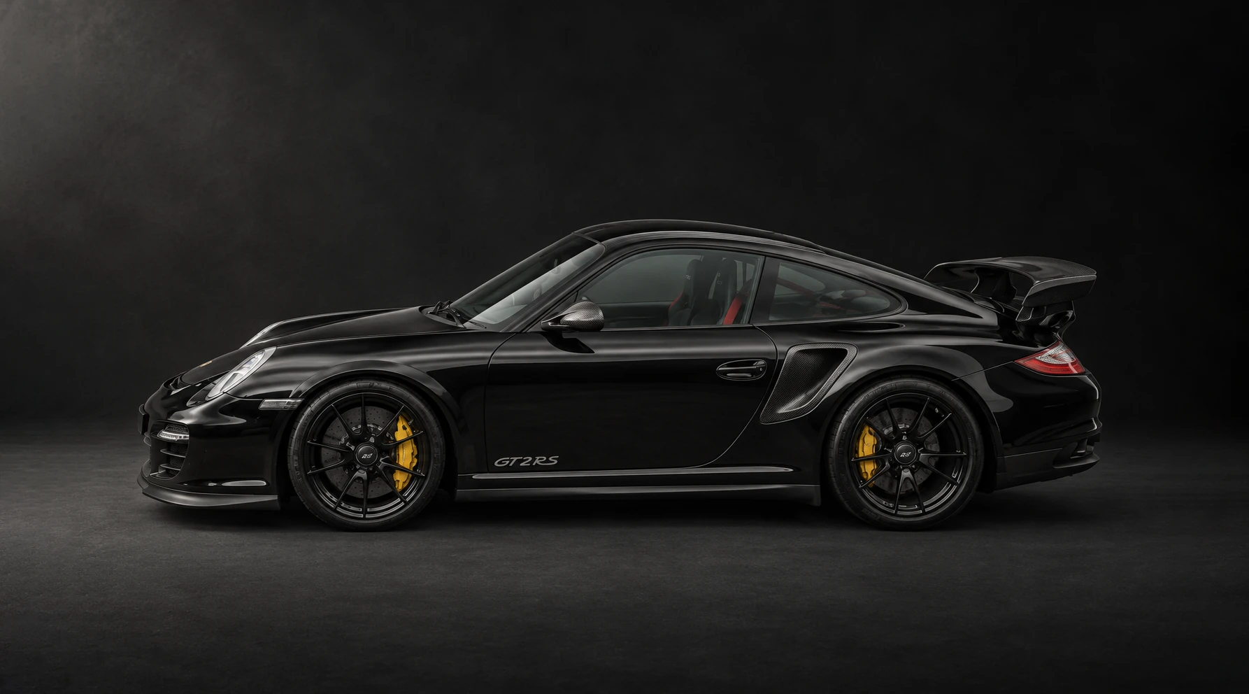 Side profile of the black Porsche 911 GT2 RS against a dark background