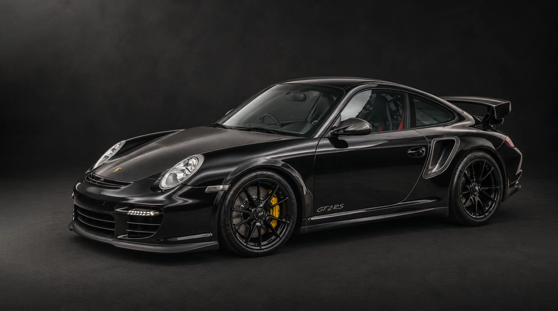 Black Porsche 911 GT2 RS, front three-quarter view, carbon-fibre bonnet and yellow ceramic brake calipers